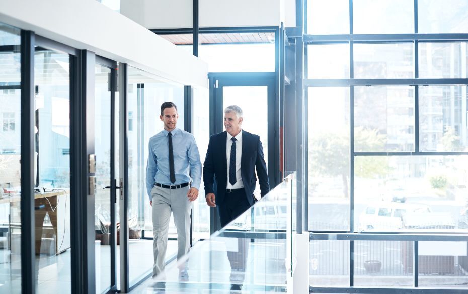 Older man walking through hallway with younger man